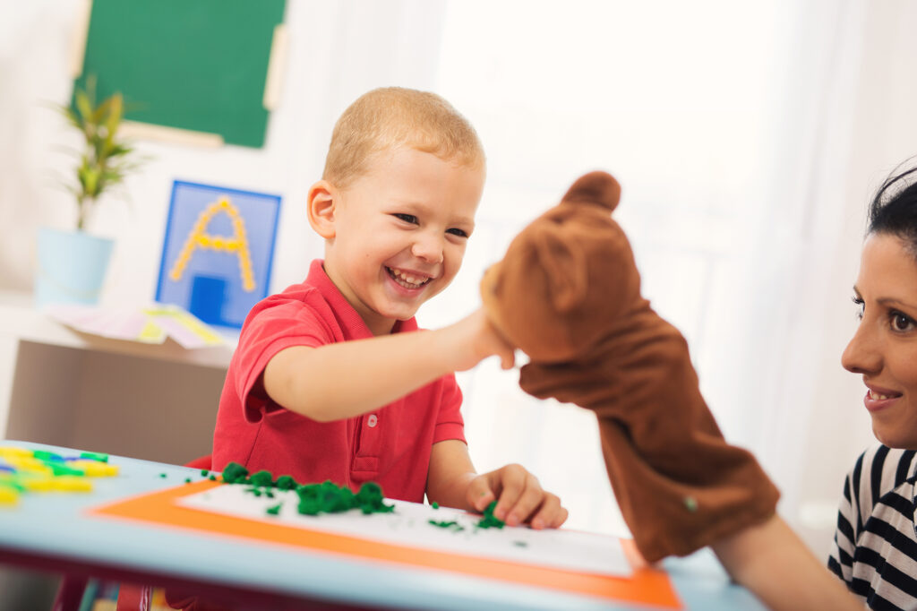 Little boy during lesson with his speech therapist. Learning thr