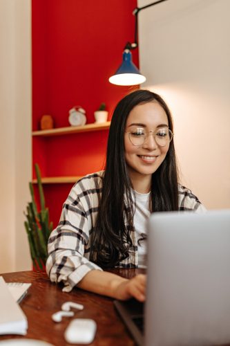 Woman with smile looks at laptop screen and poses in her comfortable office